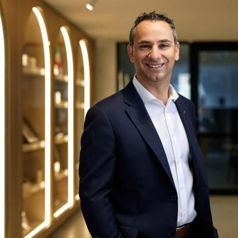 A medium shot of a man in a suit jacket and business shirt, smiling