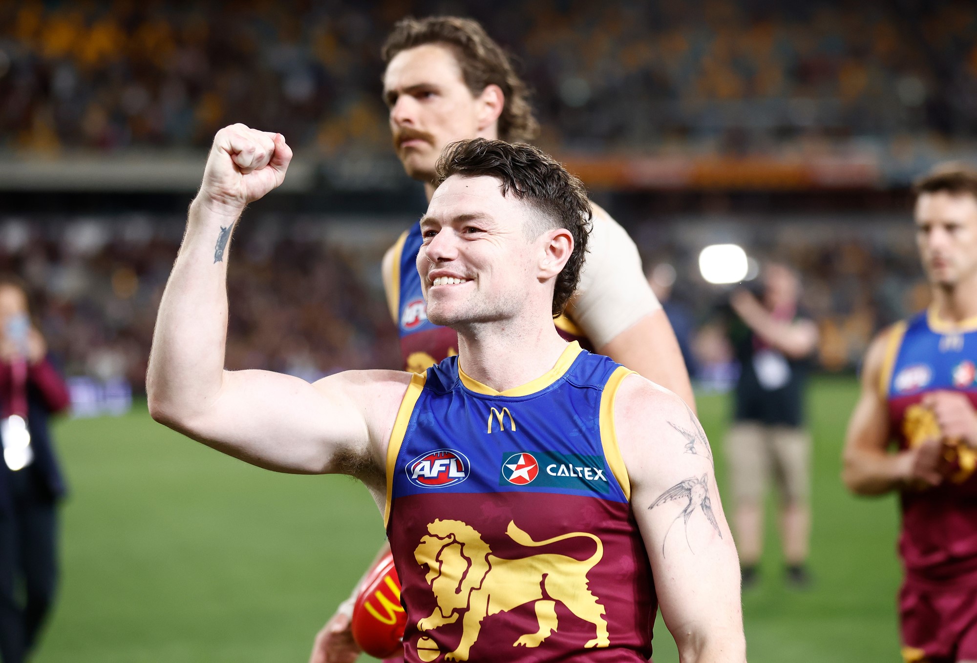 Lachie smiles on the field and holds his right fist in the air.