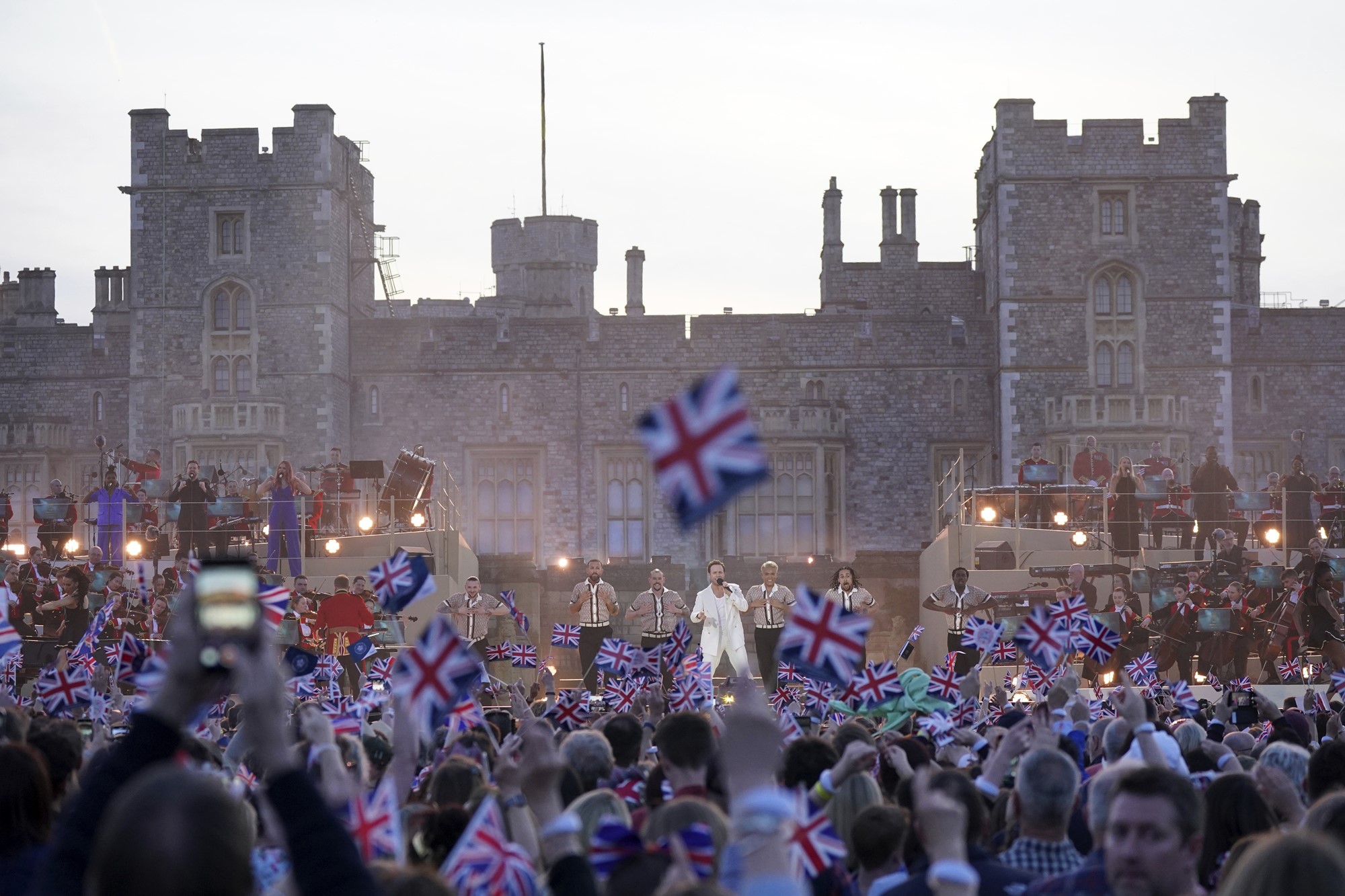 Hundreds wave flags in the air in front of a stage