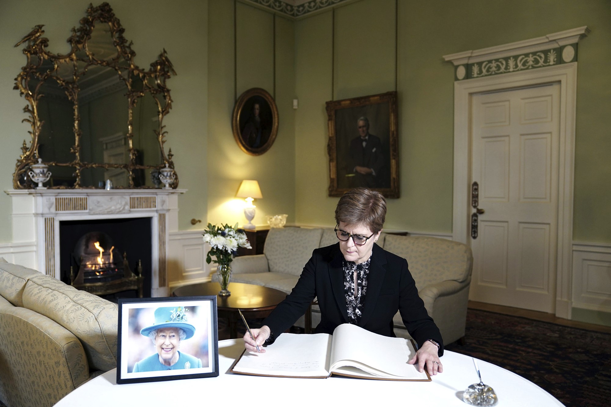 First Minister Nicola Sturgeon signs a book of condolence next to a portrait of late Queen Elizabeth II, at Bute House in Edinburgh