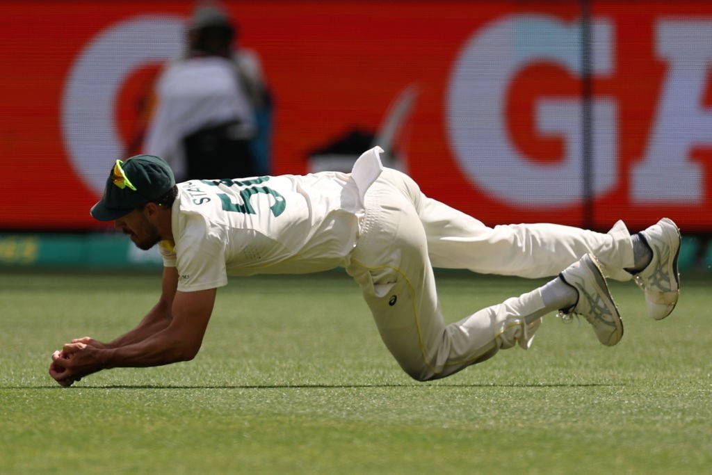 Australia fielder Mitchell Starc catches a cricket ball while diving forward during a Test against West Indies.