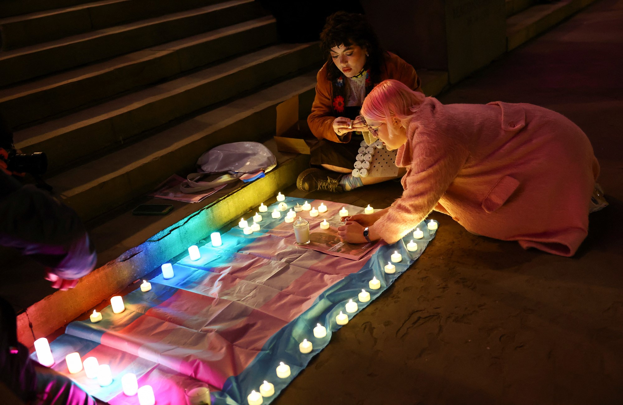 A woman places a candle on a trans flag during the vigil.