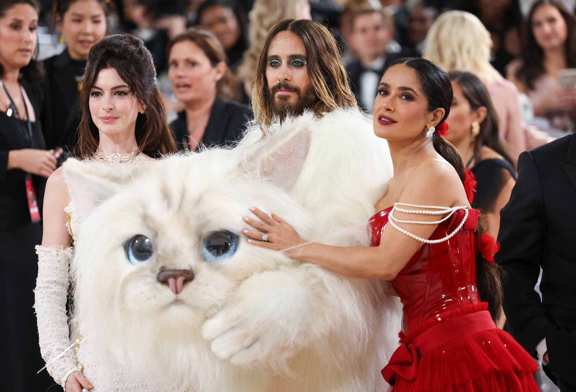 Anne, and Salma poses with Jared who is holding a giant white cat head.