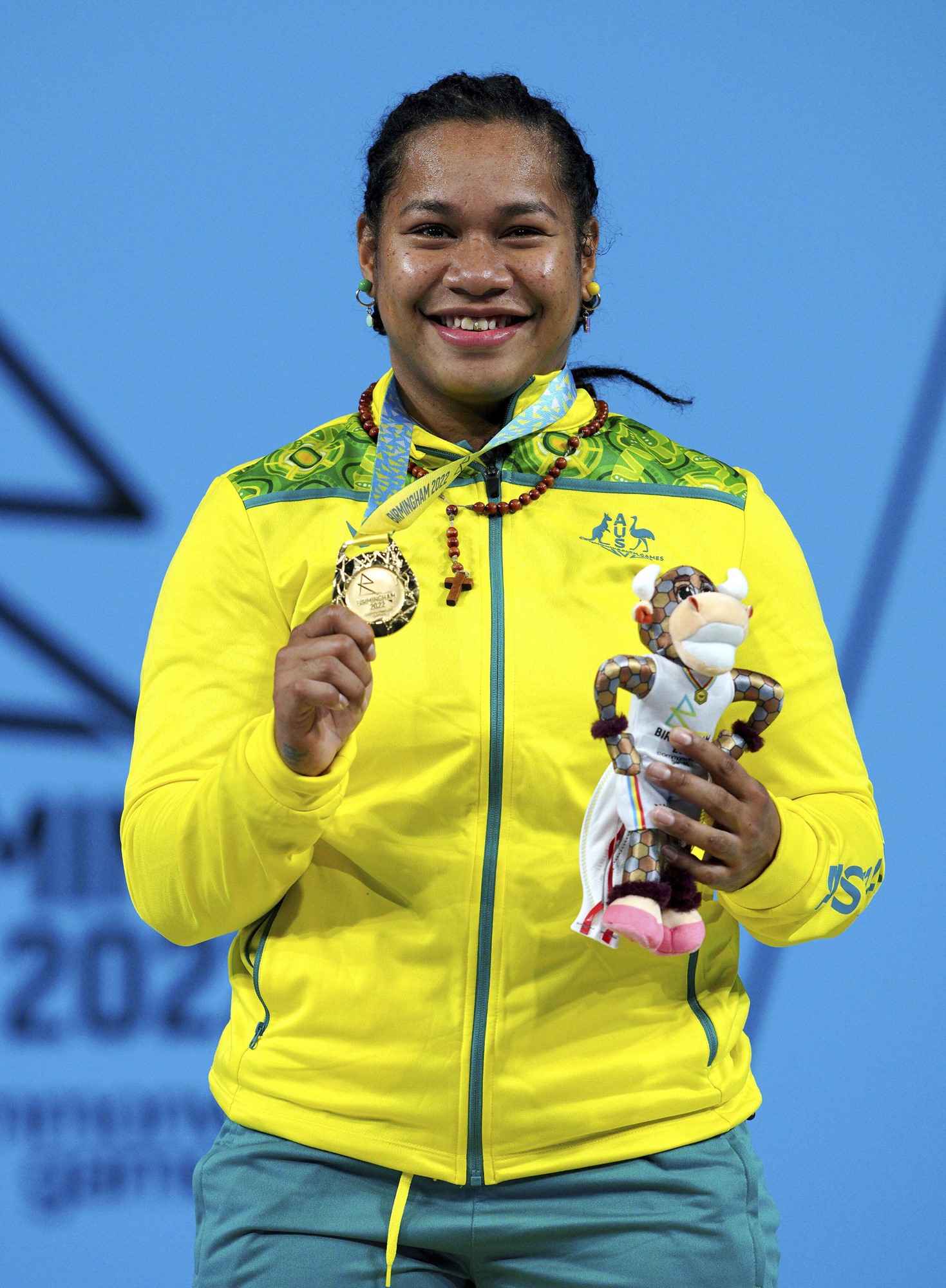 Eileen Cikamatana poses on podium with gold medal and small toy mascot