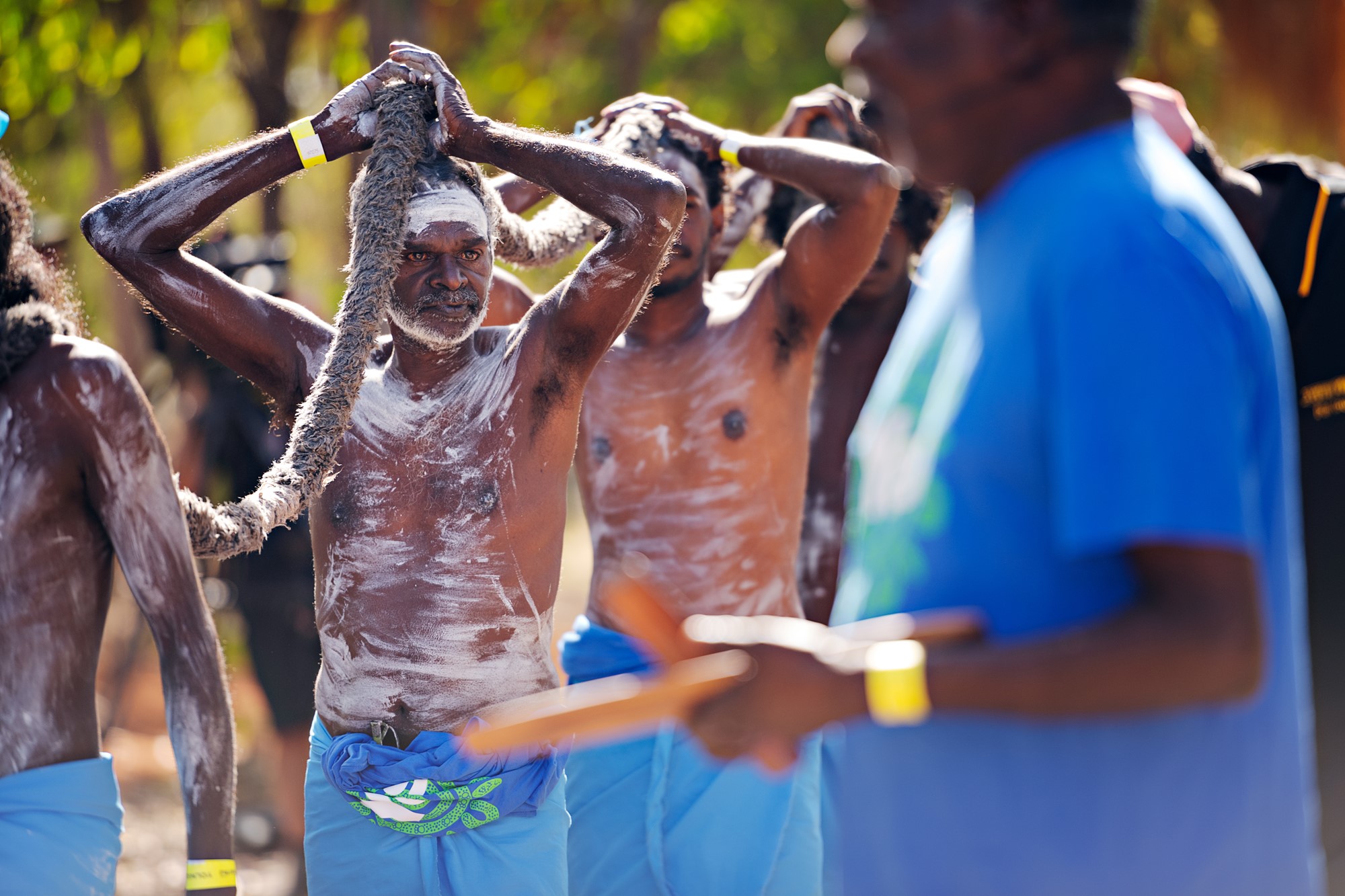 A group of Indigenous men hold a rope as they prepare to perform a dance