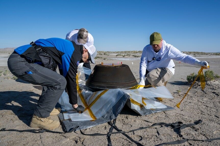 Men work around the large capsule.