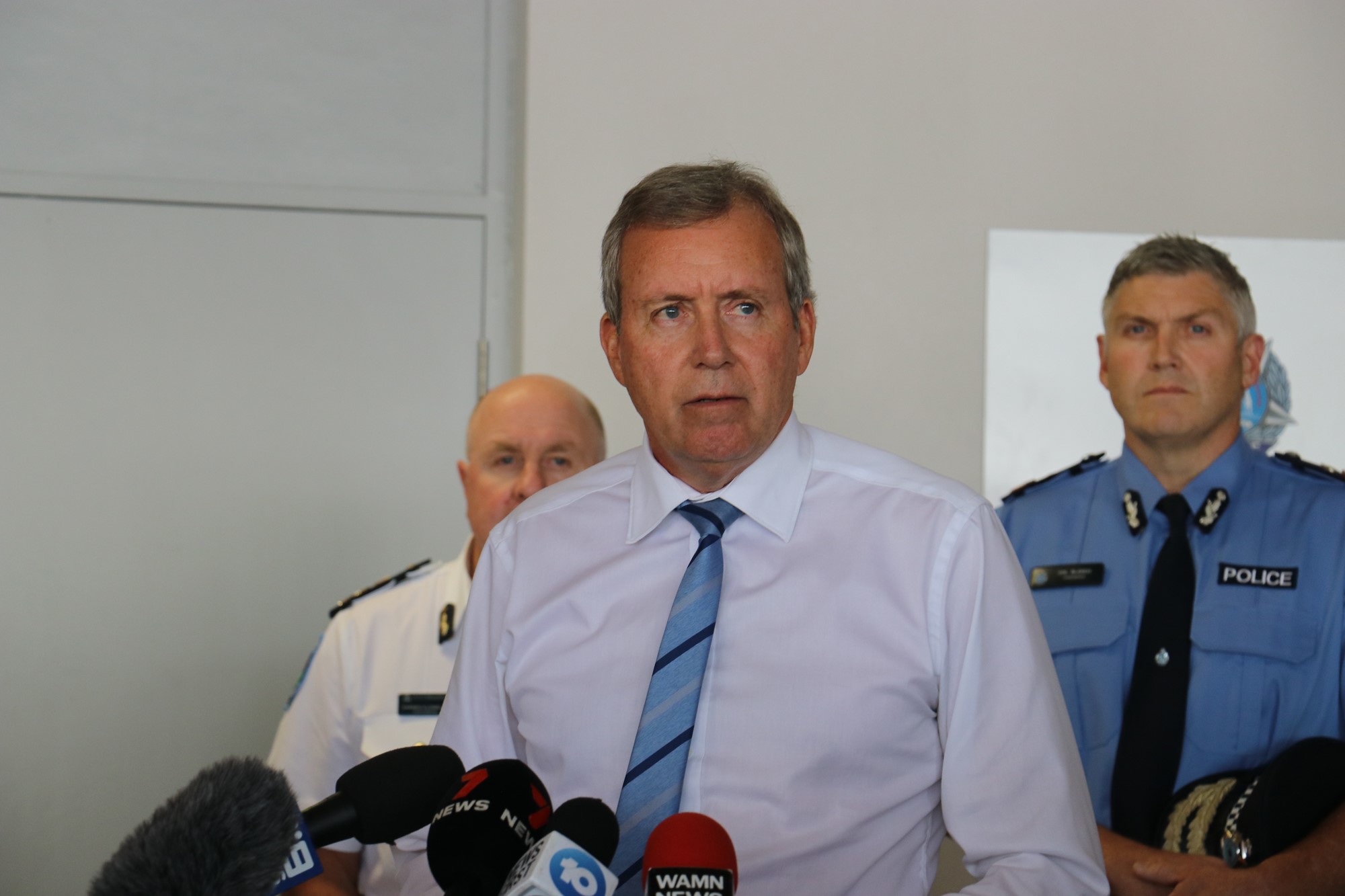 Three men stand at a press conference