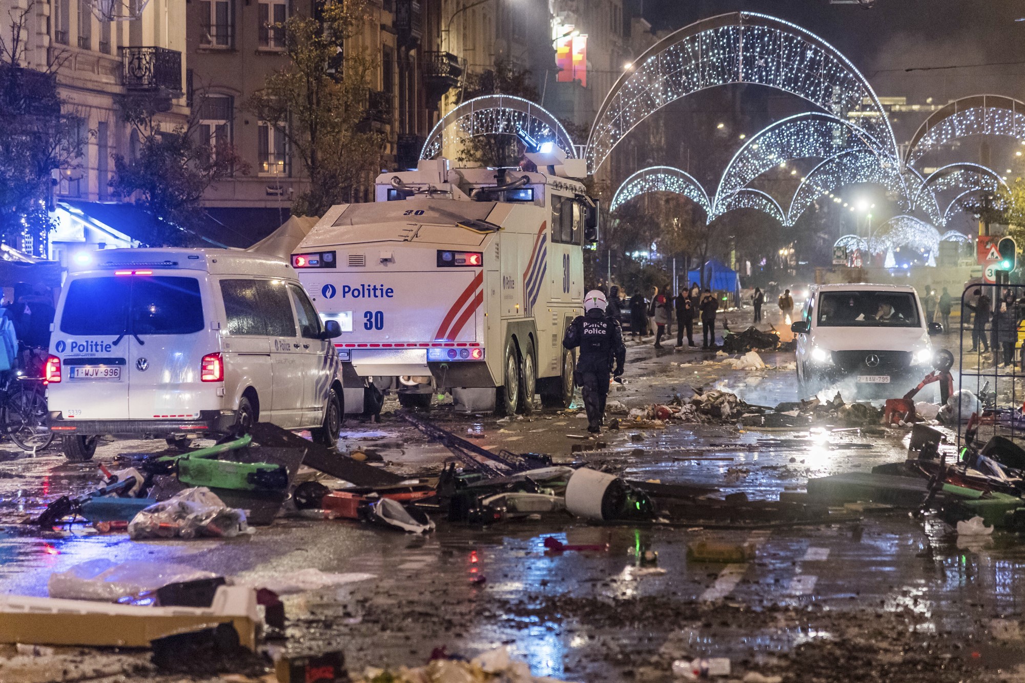 Police cars drive through a main boulevard in Brussels amid debris. 