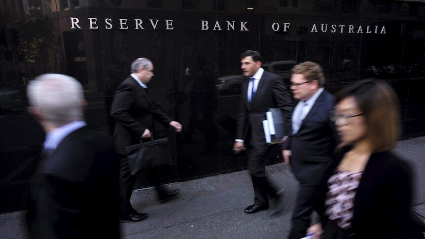 People in business wear walking in front of a wall which says 'Reserve Bank of Australia'