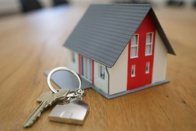 A set of keys next to a model house.