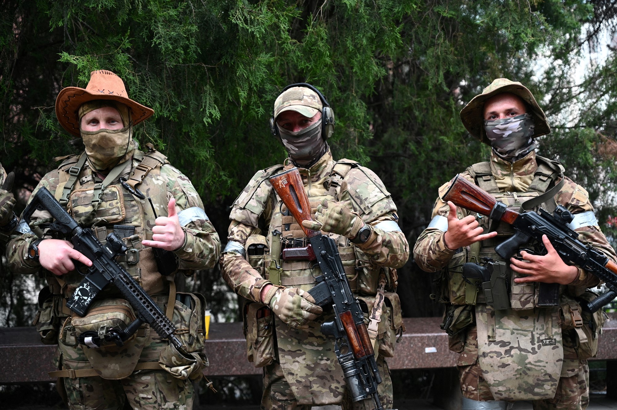 Three men in army uniforms and holding weapons standin