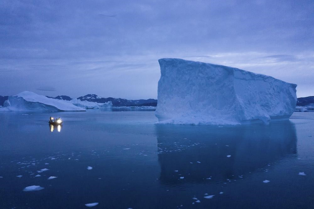 A boat navigates at night next to large icebergs in eastern Greenland on Aug. 15, 2019.