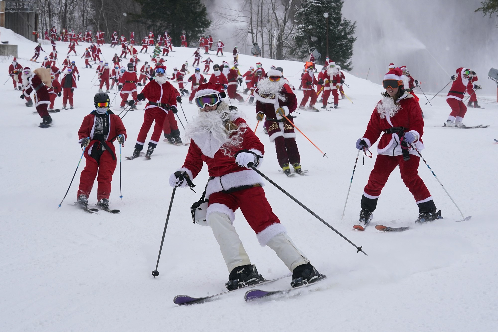 People in santa costumes ski downhill.