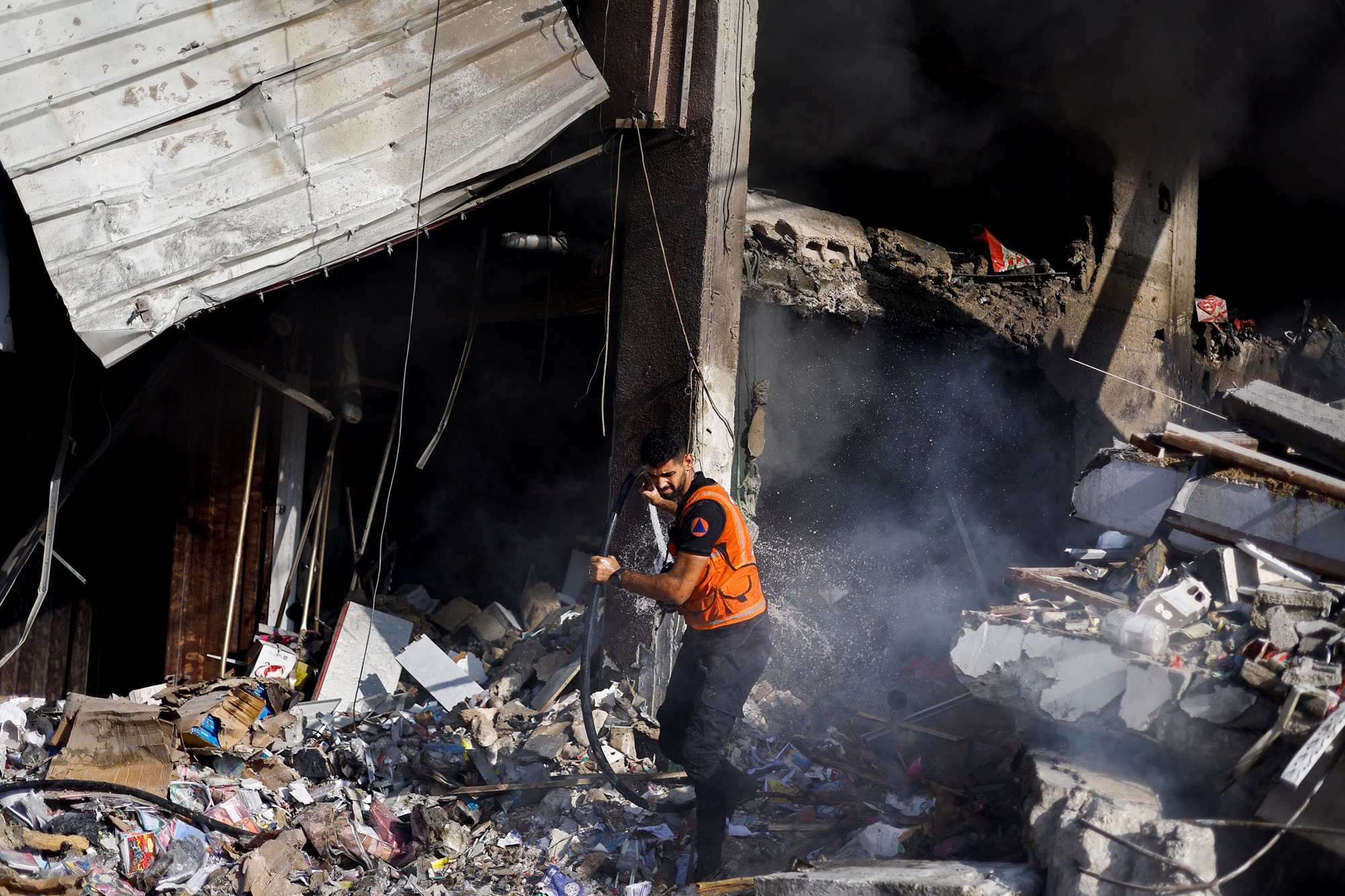 A Palestinian firefighter works to put out a fire at the site of Israeli strikes on a residential building
