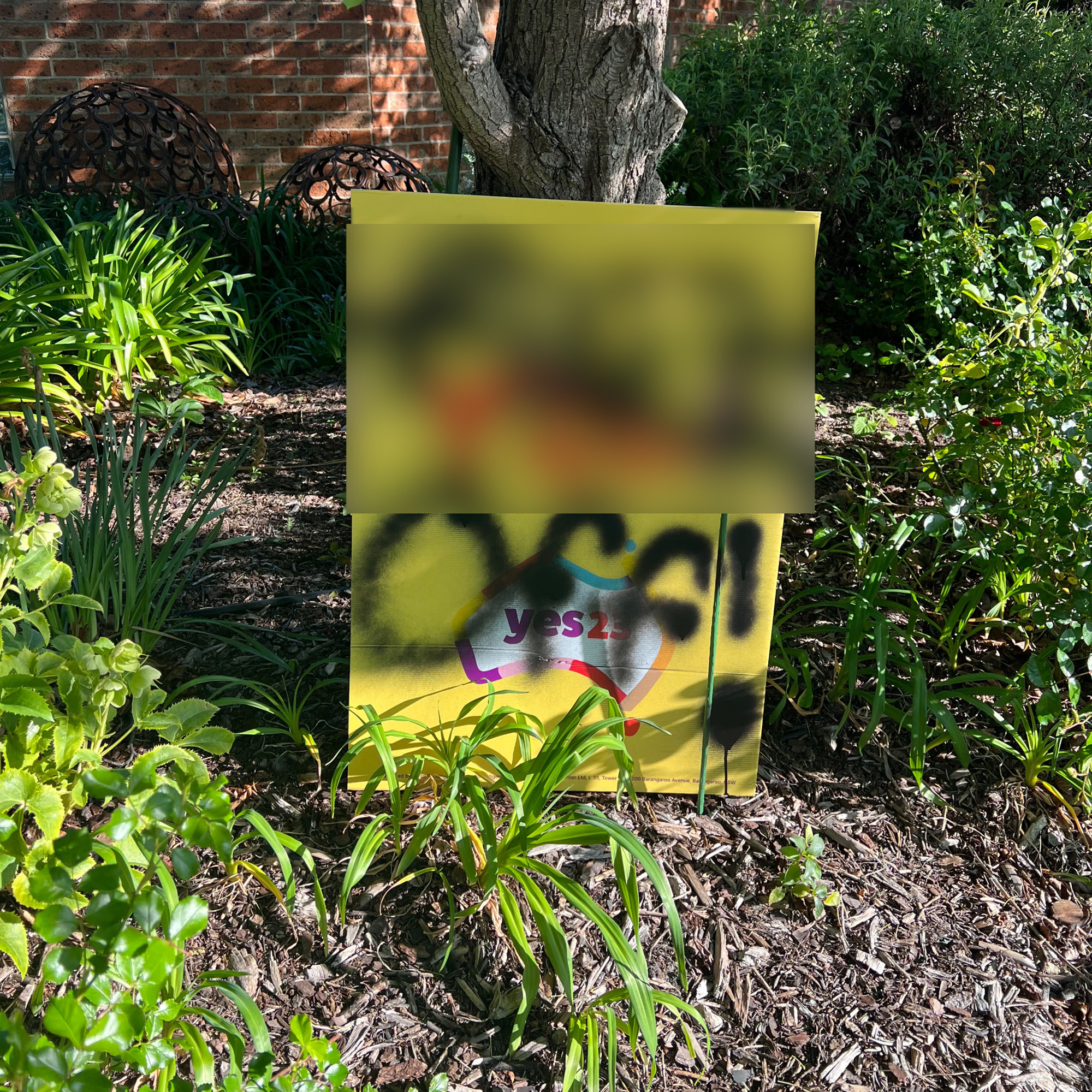 A yellow Yes sign with the phrase in question spray painted on, which has been blurred before publishing.