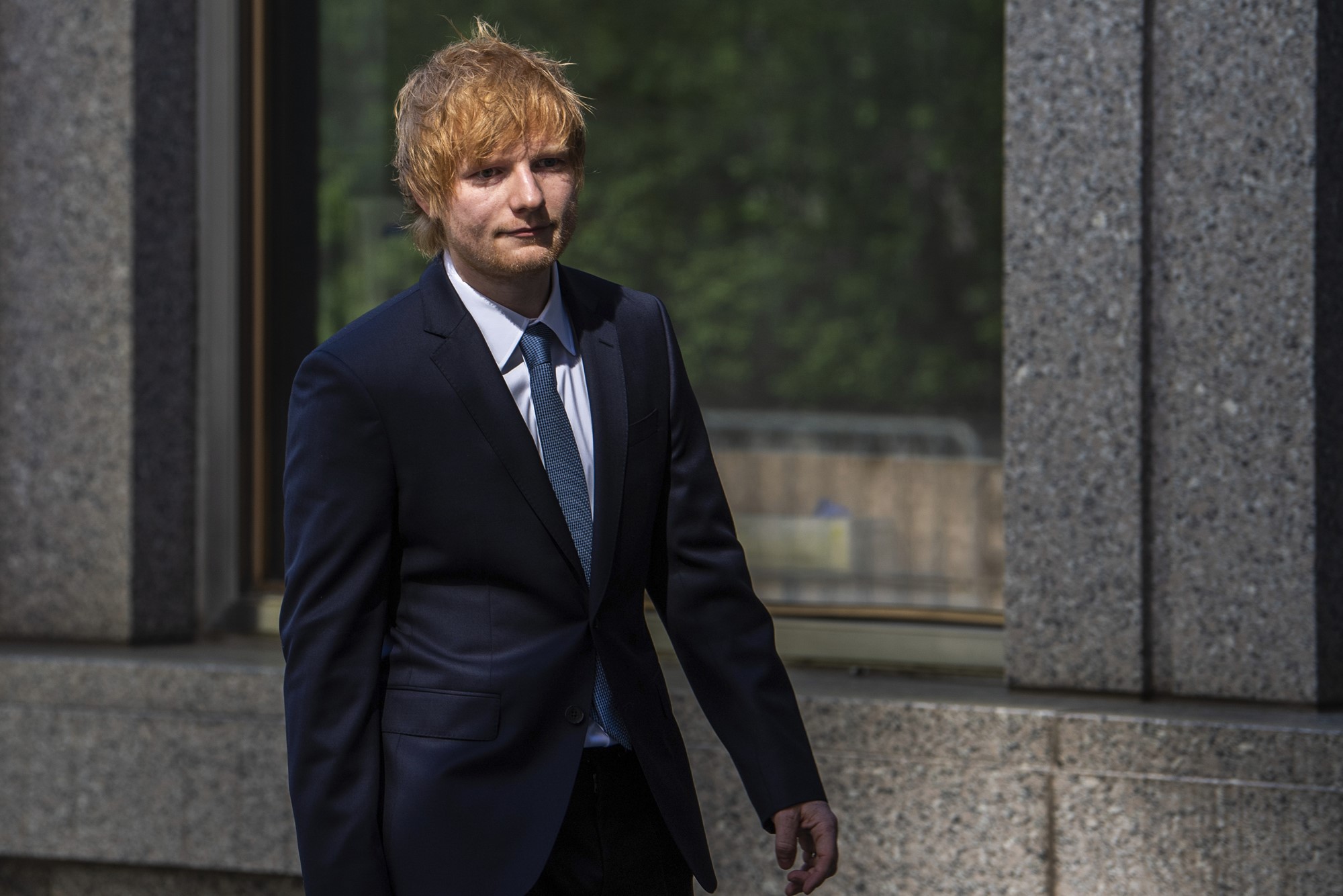 Ed Sheeran walking, wearing a suit.