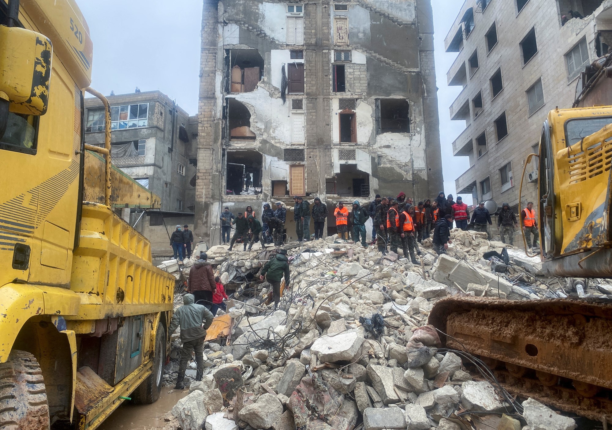 Rescuers search for survivors under the rubble of a collapsed building, following an earthquake, in Hama, Syria