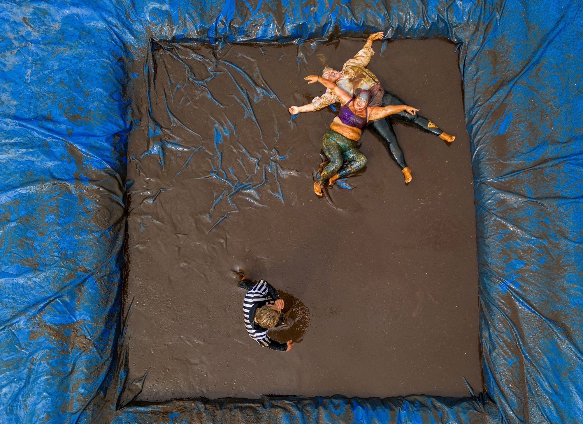 Aerial shot of two people wrestling in a pool  of gravy