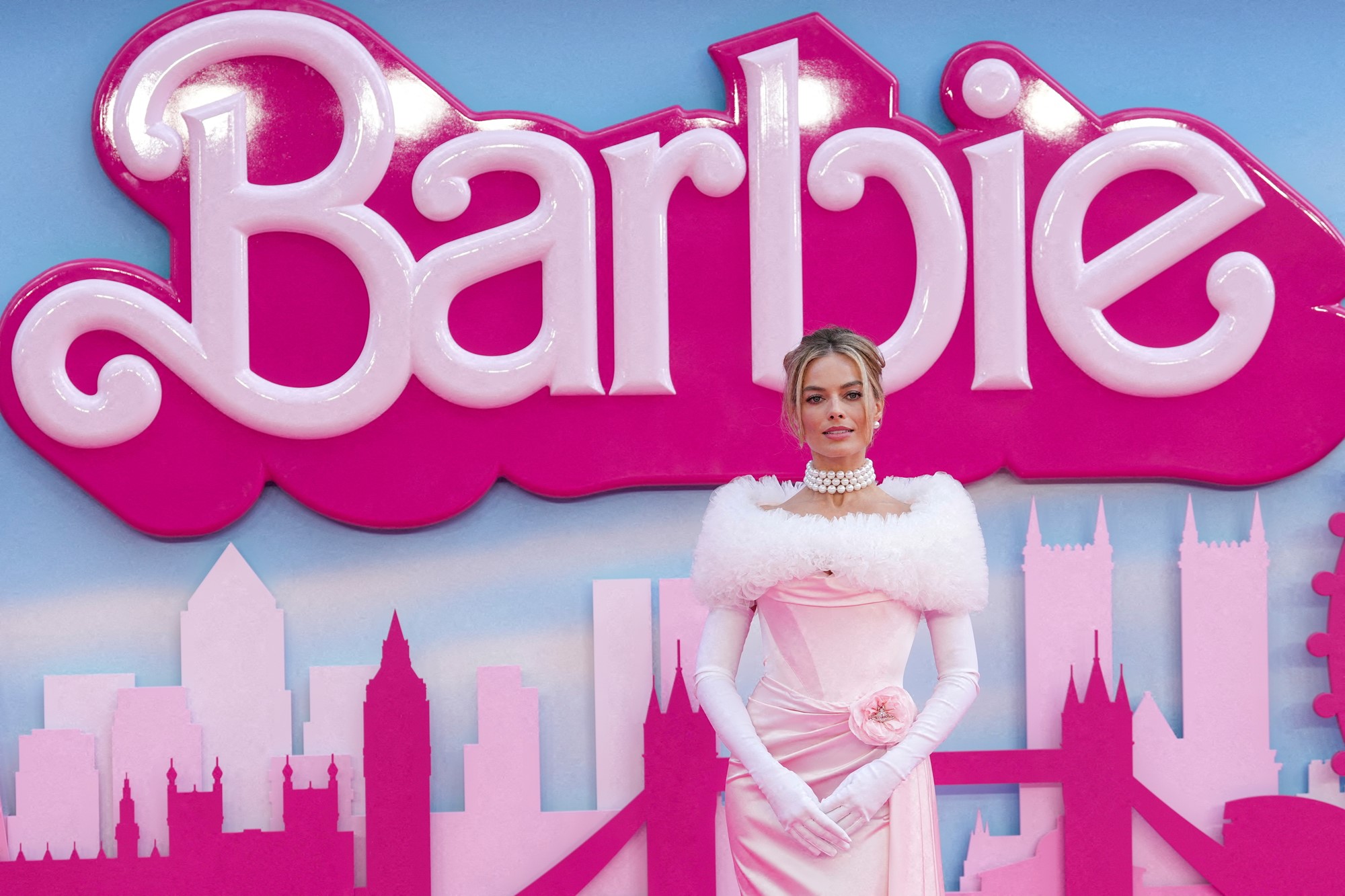 Margot robbie in a pink dress in front of a barbie premiere back drop 