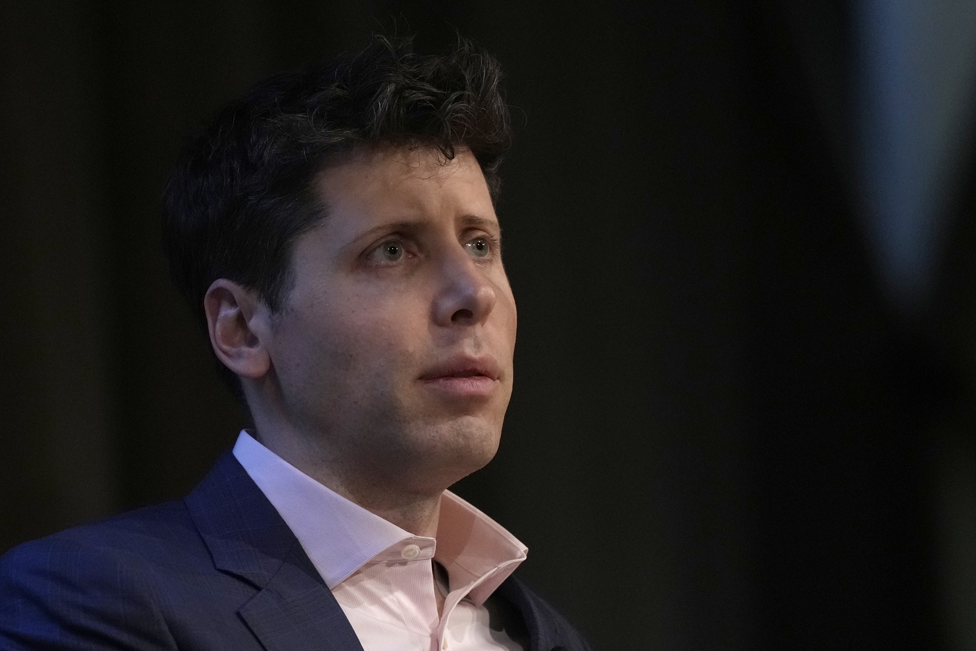 A white man in a suit and collared shirt, with dark hair