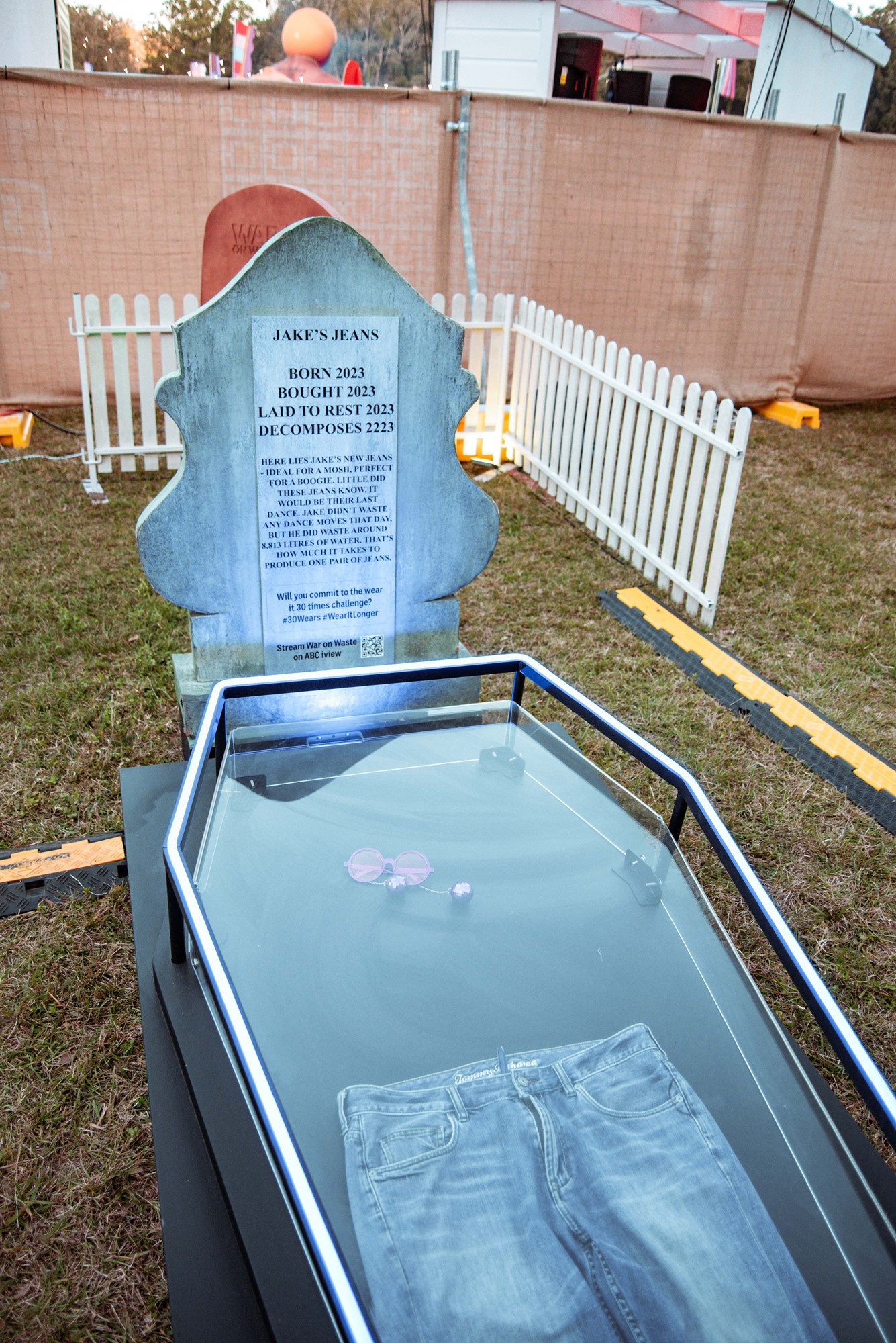 A fake glass coffin with a headstone for a pair of jeans showing how long they'll take to break down