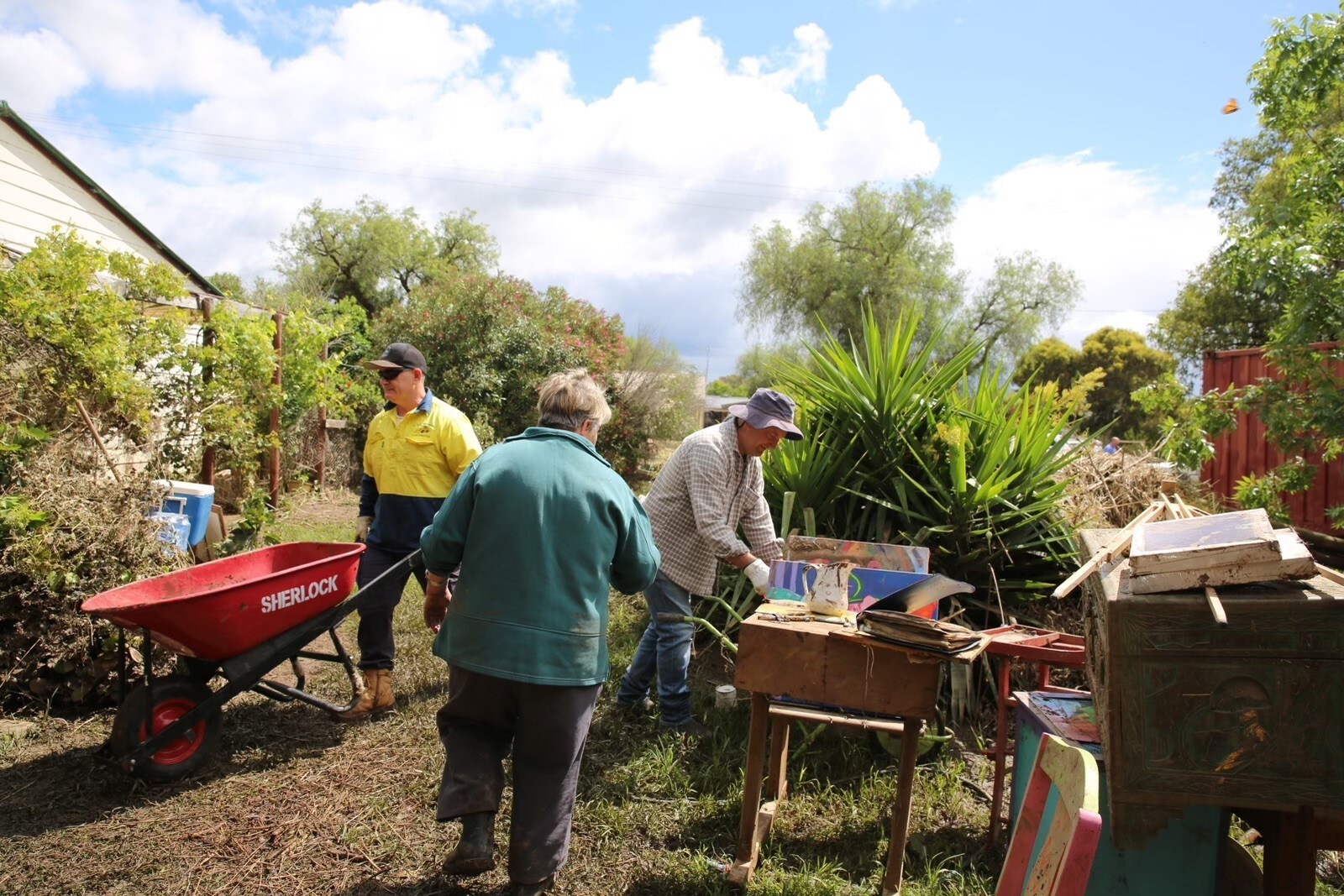 A man pushes a full wheelbarrow as a woman stands by.