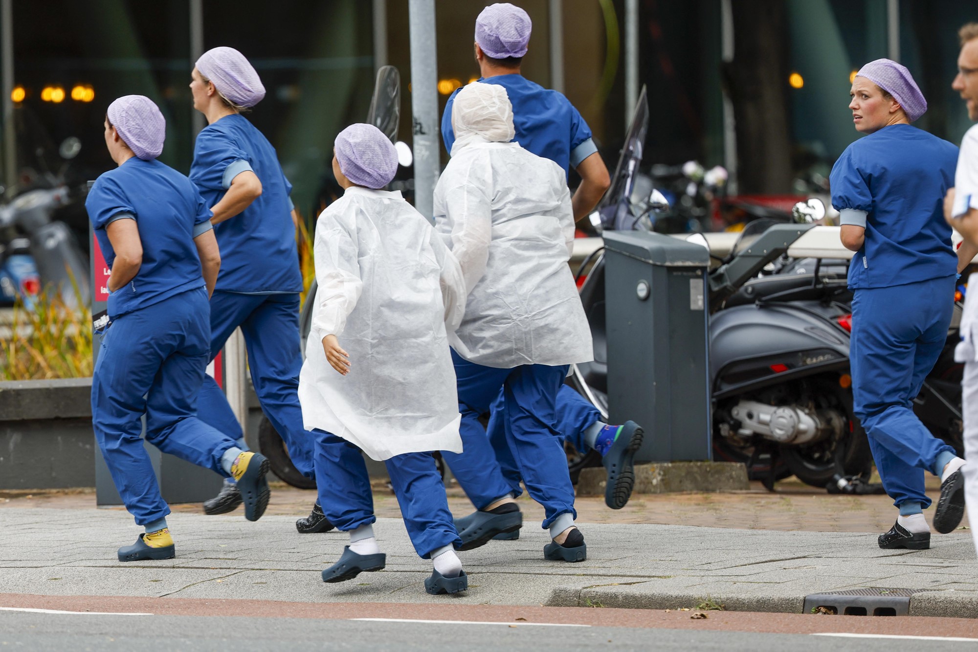 Medical staff rush outside in their blue scrubs.