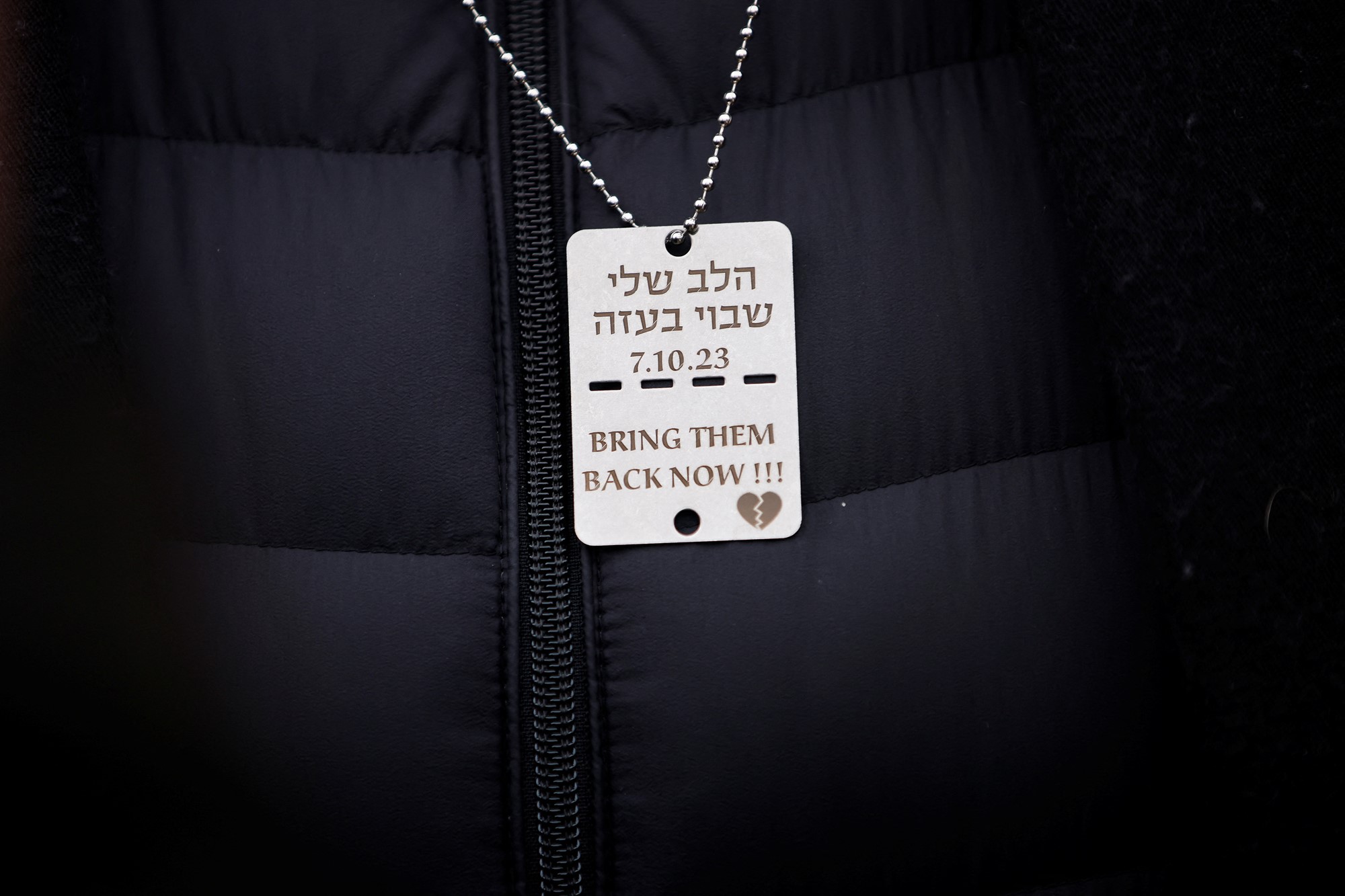 Close up of dog tag with Hebrew and says 'bring them back now!!! 