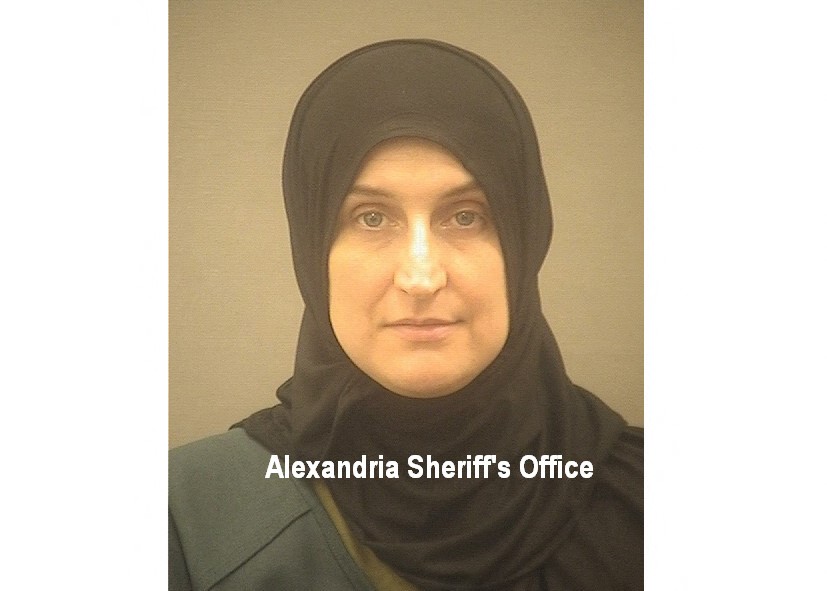 A woman with a black hijab looks front on at the camera in a police photo.
