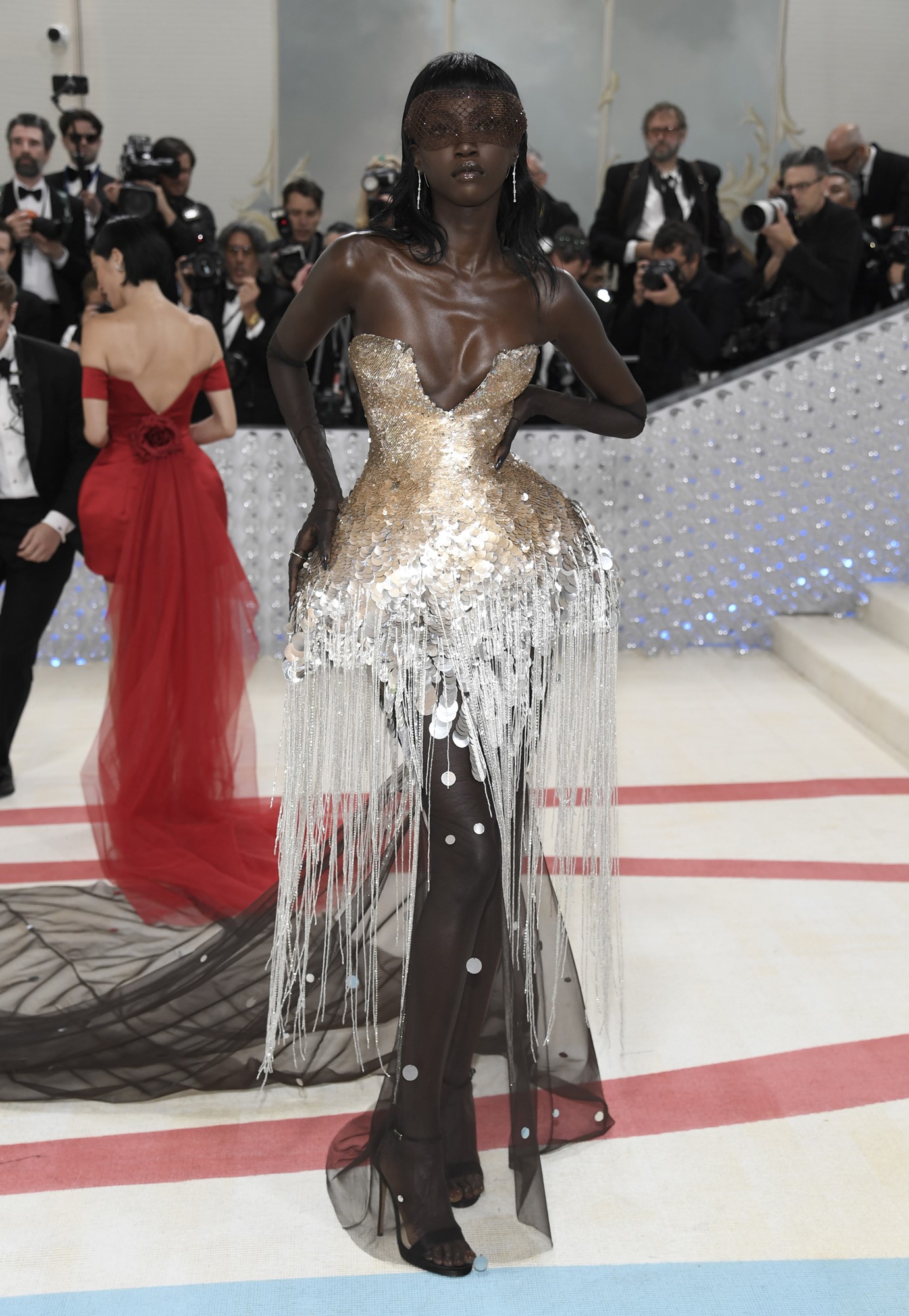 Anok wears a gold and silver gown.