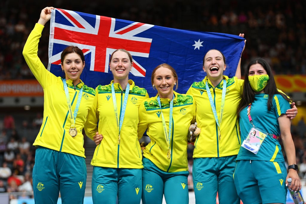 Four women hold an Australian flag in the air