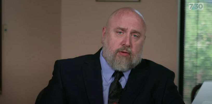 a middle aged man with a beard being interviewd on camera