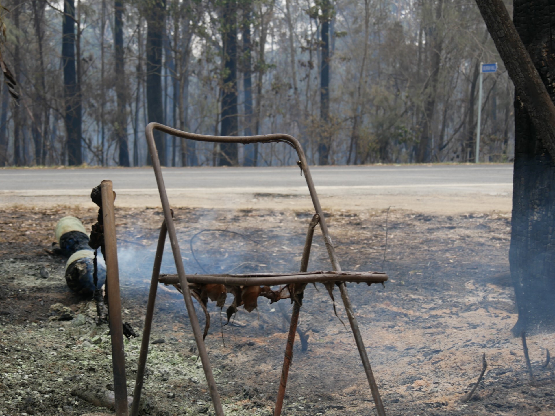 Burnt chair in a paddock still smoldering. 