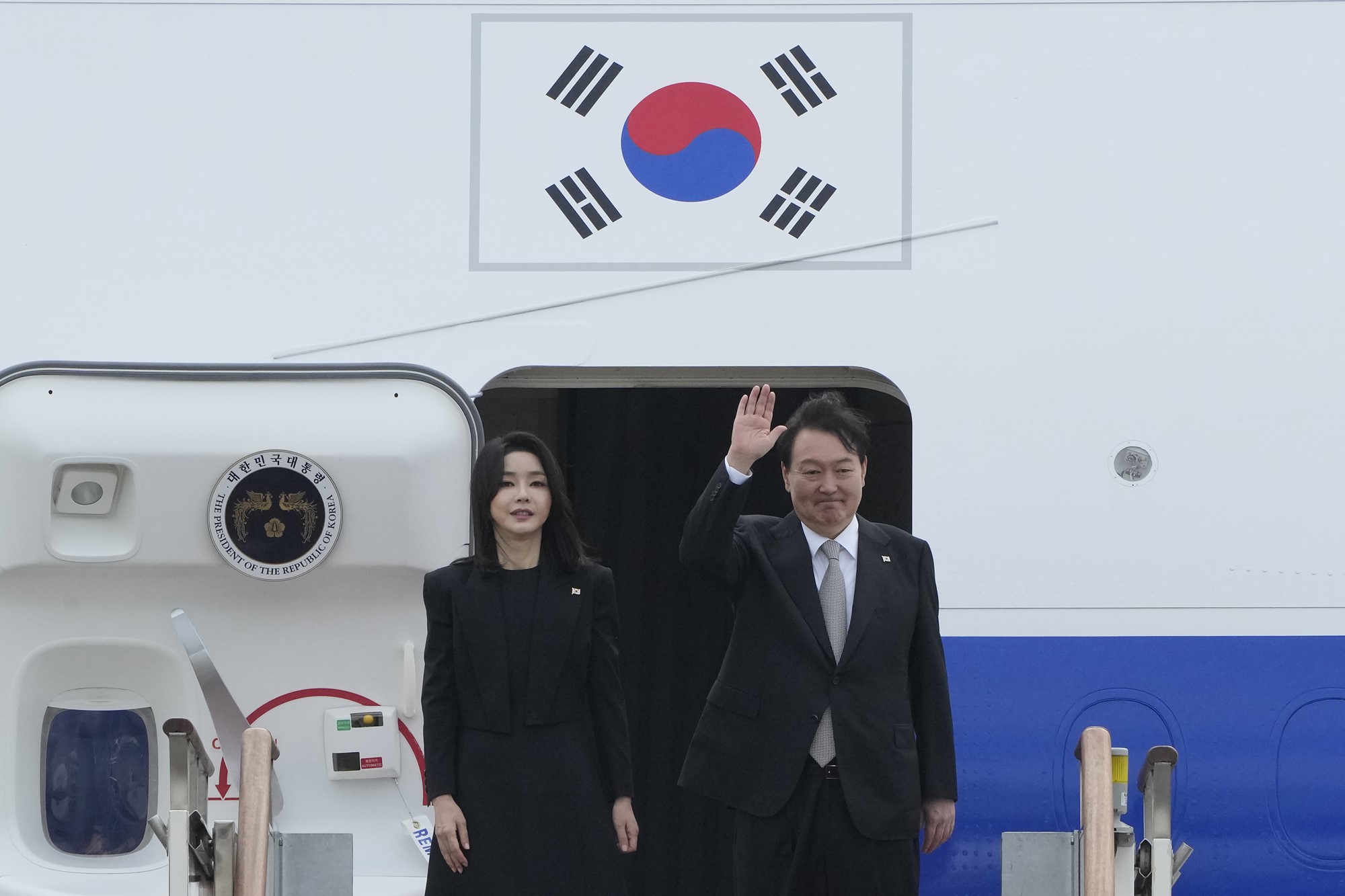 South Korean President Yoon Suk Yeol waves as his wife Kim Keon Hee boarding a plane with the South Korean flag on it