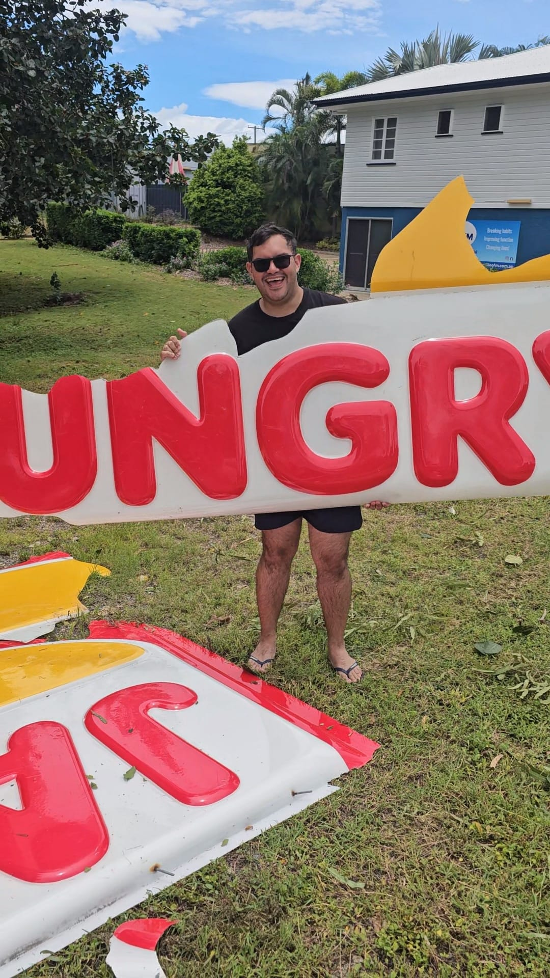 a man holding a broken hungry jacks sign