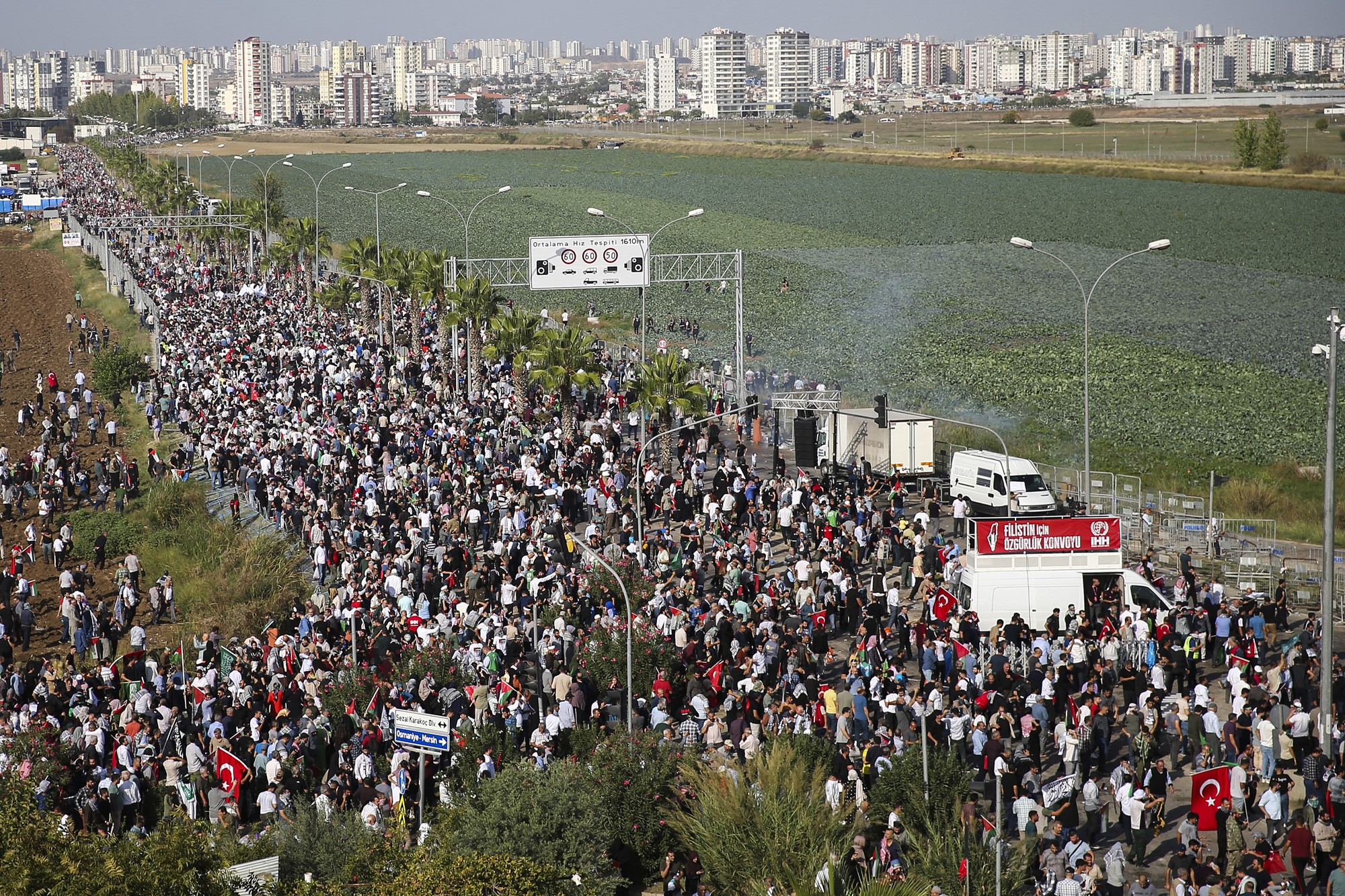 A picture taken from high up shows thousands of protesters gathered on a road, a large city and a field can be seen in the background