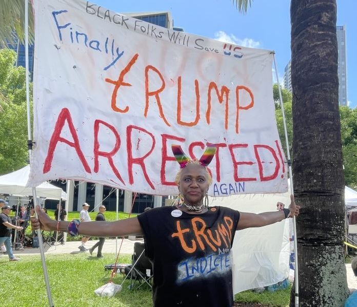 An anti-Trump protester standing in front of a banner. 