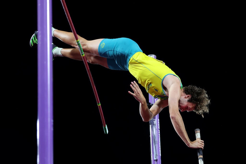 A man knocks the pole off its stand while pole vaulting