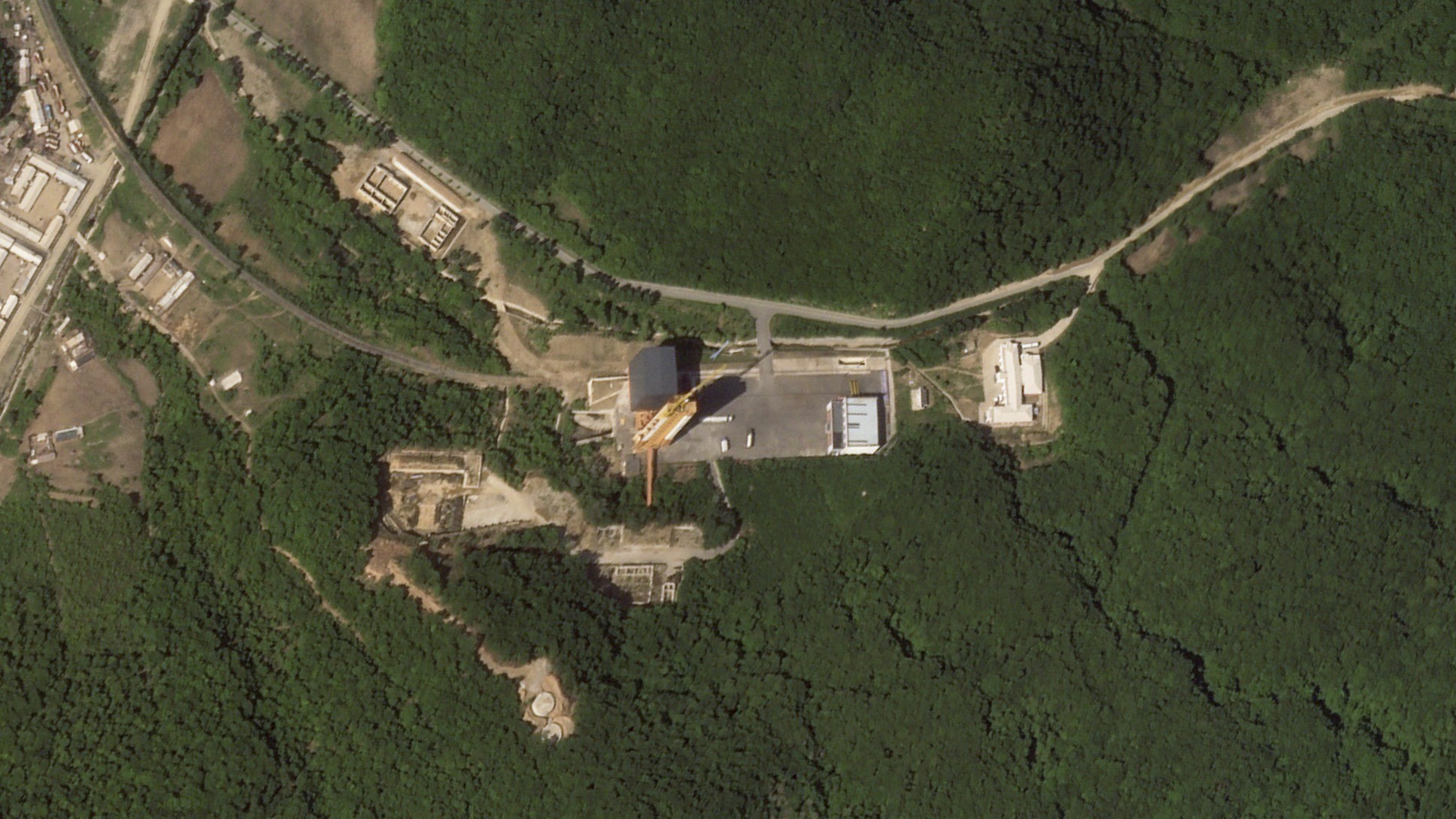 Overhead aerial satellite photo of a rocket launchpad near roads and trees